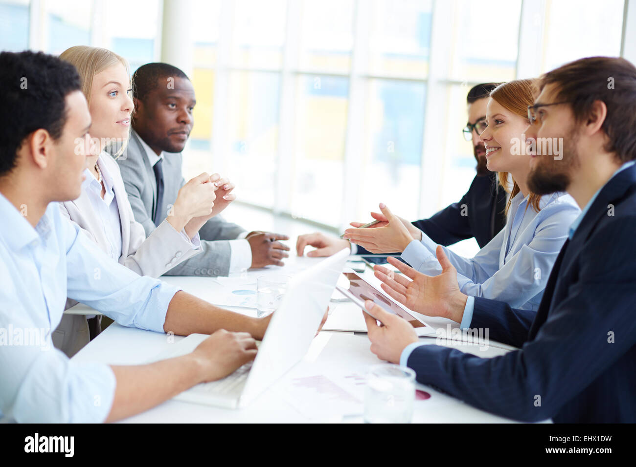 Two groups of people sitting opposite and communicating Stock Photo