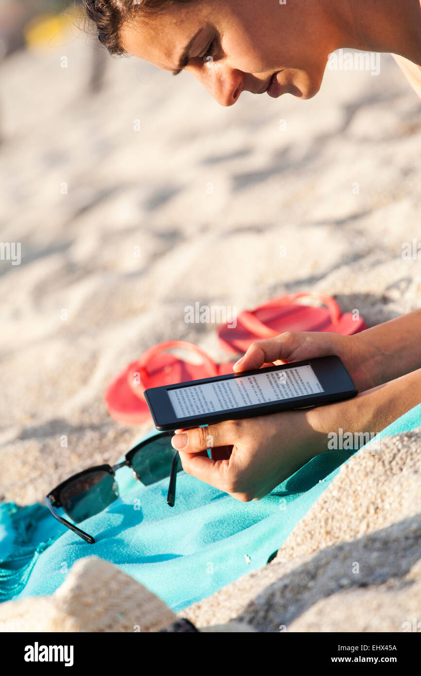 Greece, young woman reading e-book on the beach Stock Photo