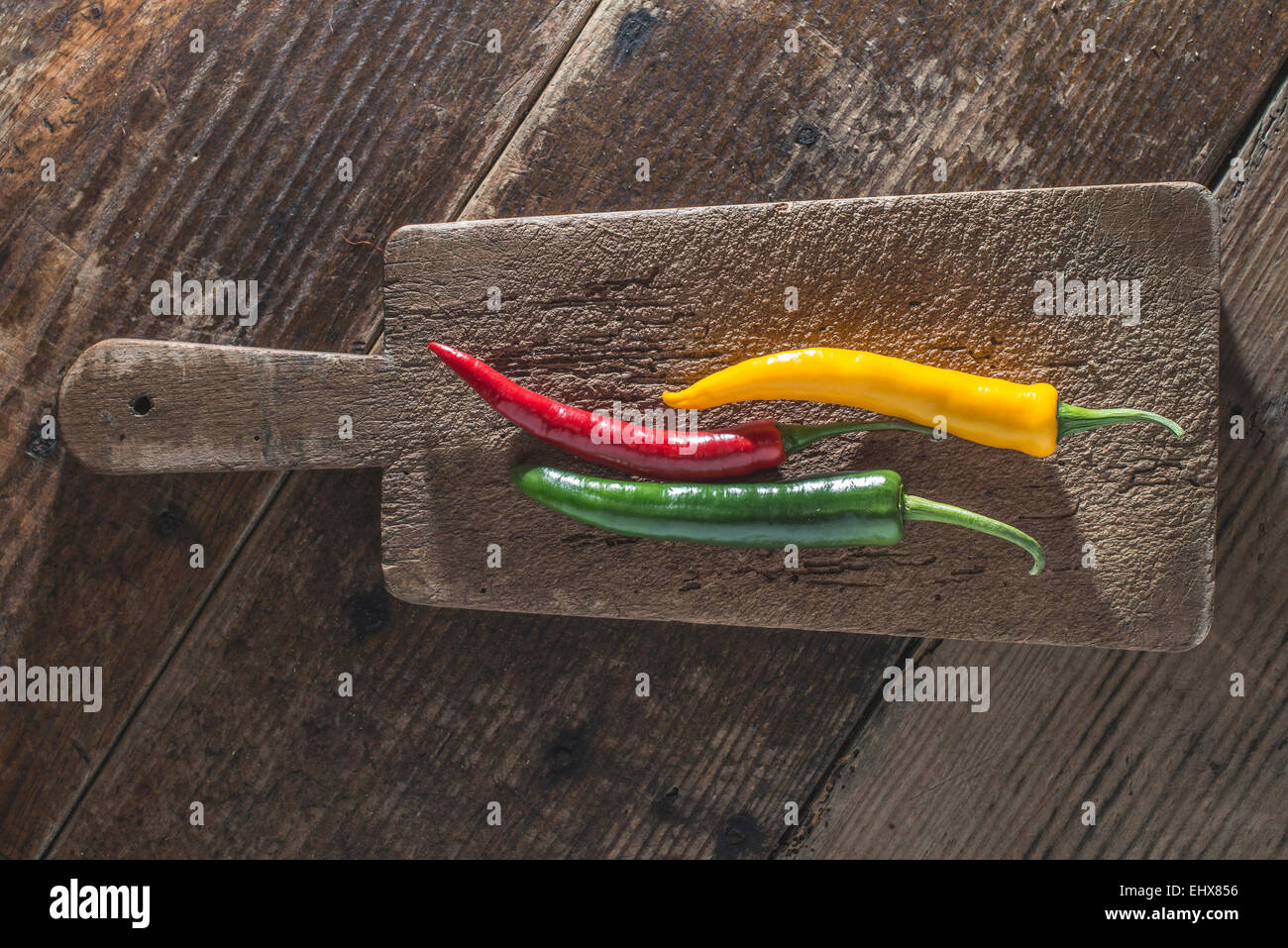 Three chili peppers on old wooden board Stock Photo - Alamy