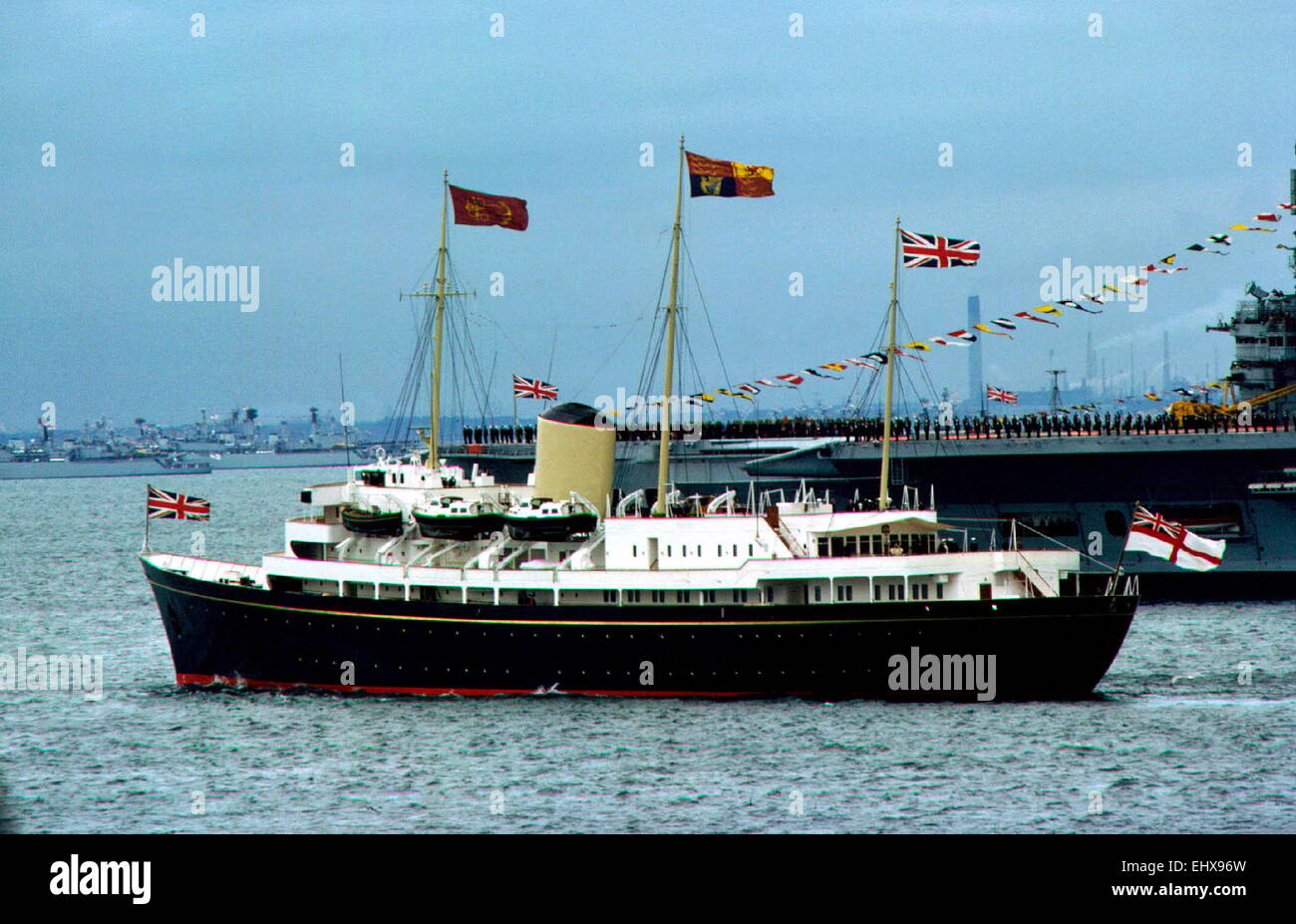 AJAX NEWS PHOTOS. 1977. SPITHEAD, ENGLAND. - ROYAL YACHT - THE ROYAL YACHT BRITANNIA WITH H.M.QUEEN ELIZABETH II EMBARKED, SAILS PAST THE AIRCRAFT CARRIER HMS ARK ROYAL DURING THE 1977 SILVER JUBILEE FLEET REVIEW.  PHOTO:JONATHAN EASTLAND/AJAX REF:SJ FLEET 1977 Stock Photo