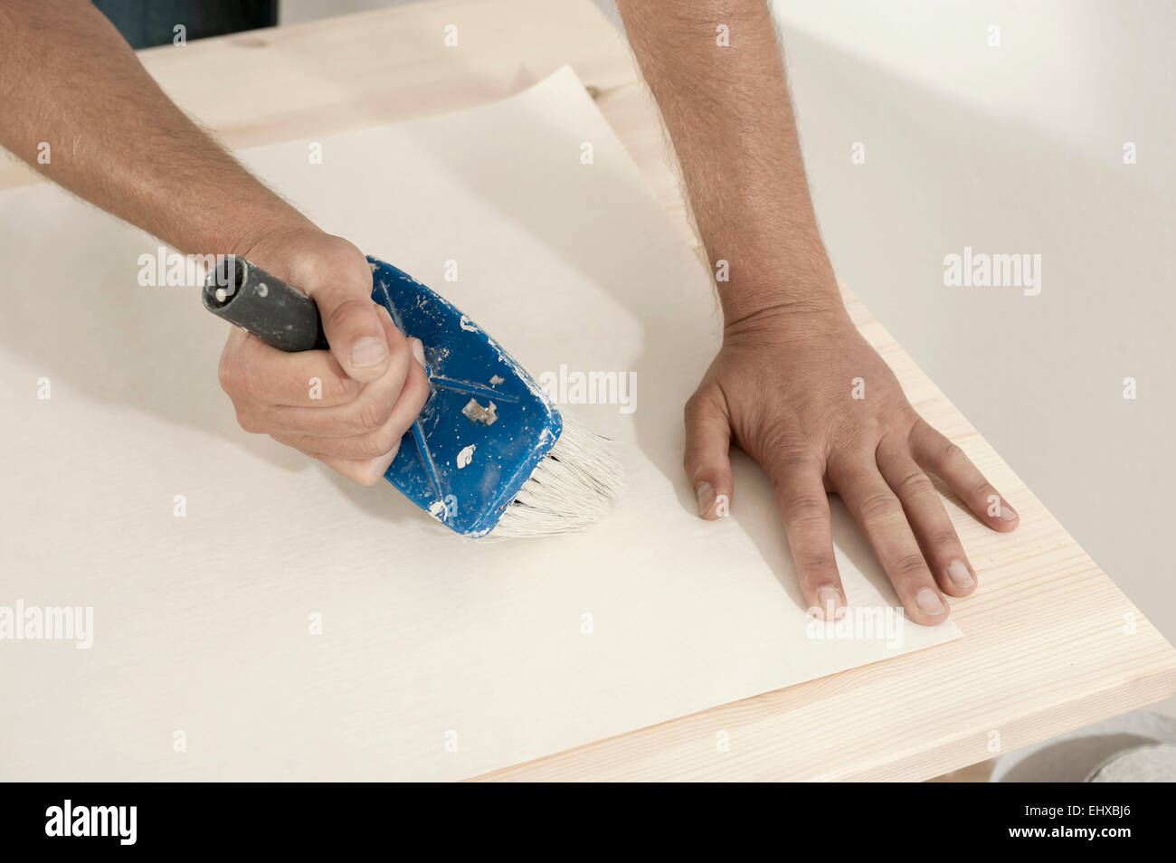 Man applying glue on wallpaper with a brush, Bavaria, Germany Stock Photo