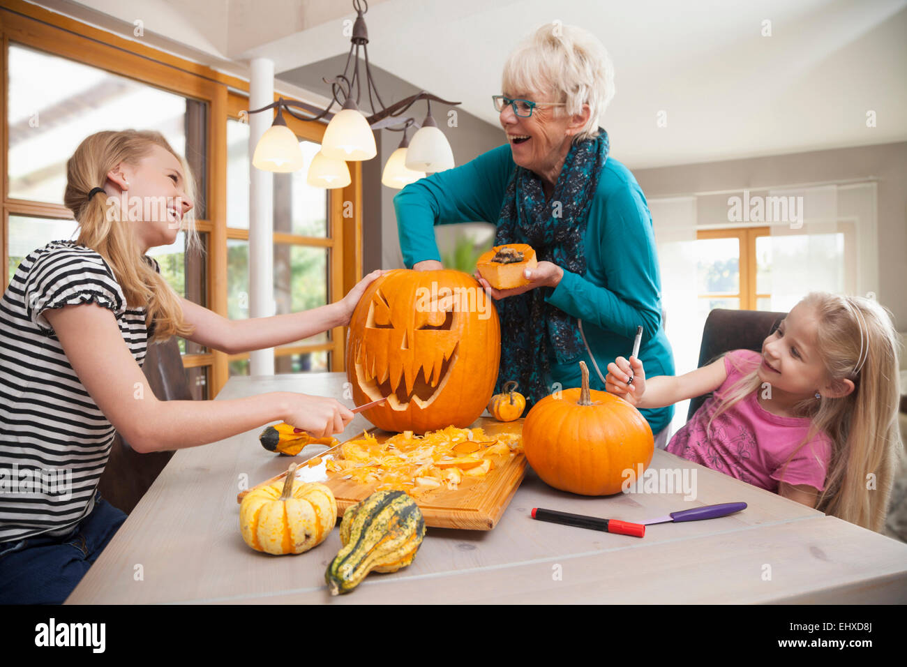 Senior woman carving pumpkin for Halloween with her granddaughters, Bavaria, Germany Stock Photo