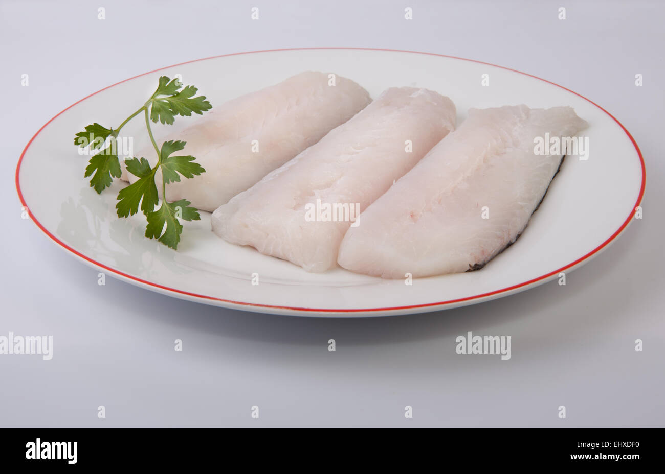 Boneless hake steaks on plate with parsley Stock Photo Alamy