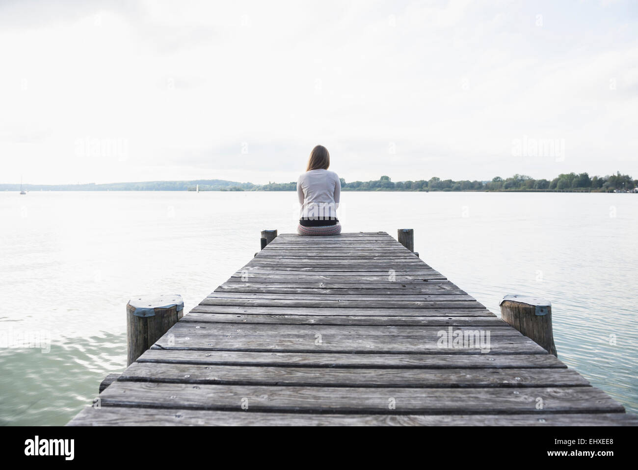 Woman alone sitting jetty lake tranquil Stock Photo