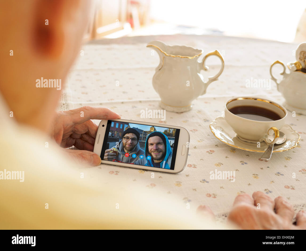 Grandfather videoconferencing with grandson and friend via smartphone Stock Photo