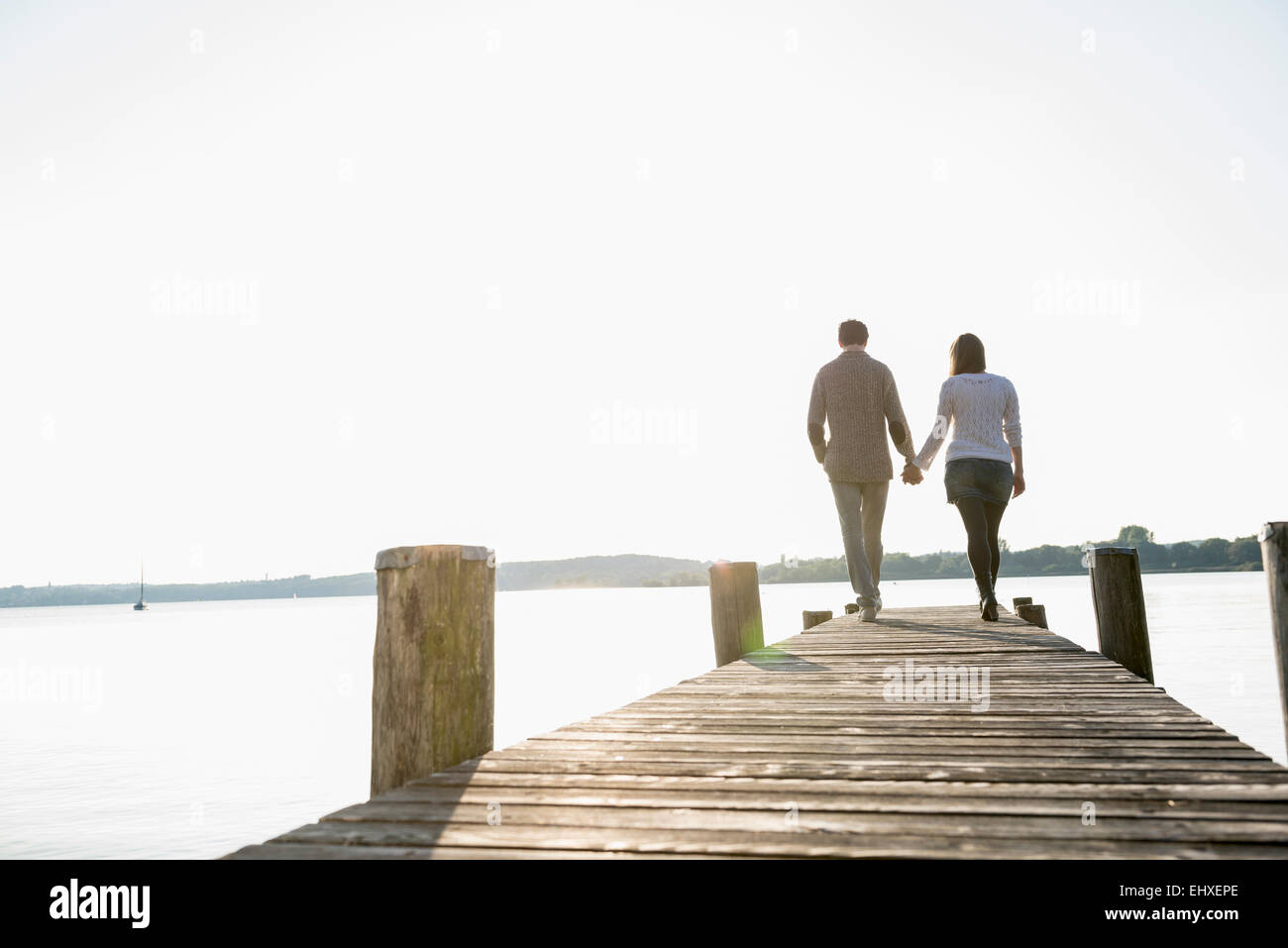 Couple walking on wooden jetty sunset Stock Photo
