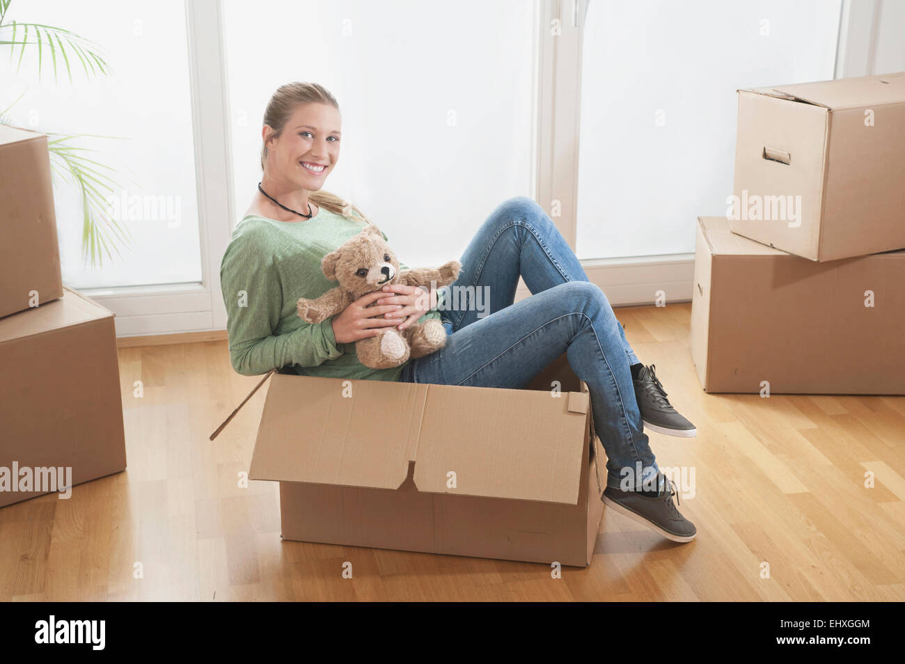 Young woman sitting in a cardboard box and smiling, Bavaria, Germany ...