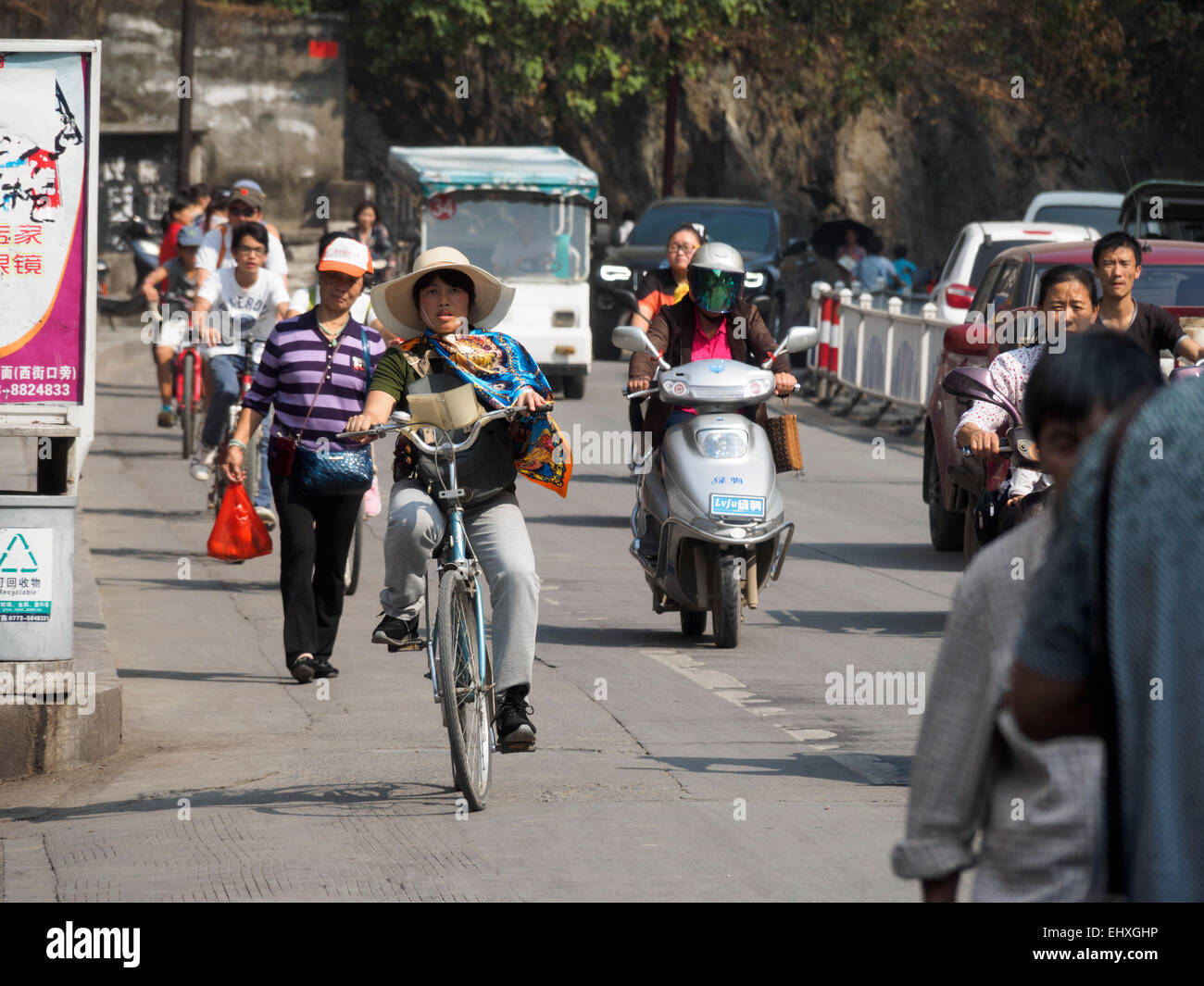 People riding bikes and motorized scooters on the streets of Yangshuo, China Stock Photo