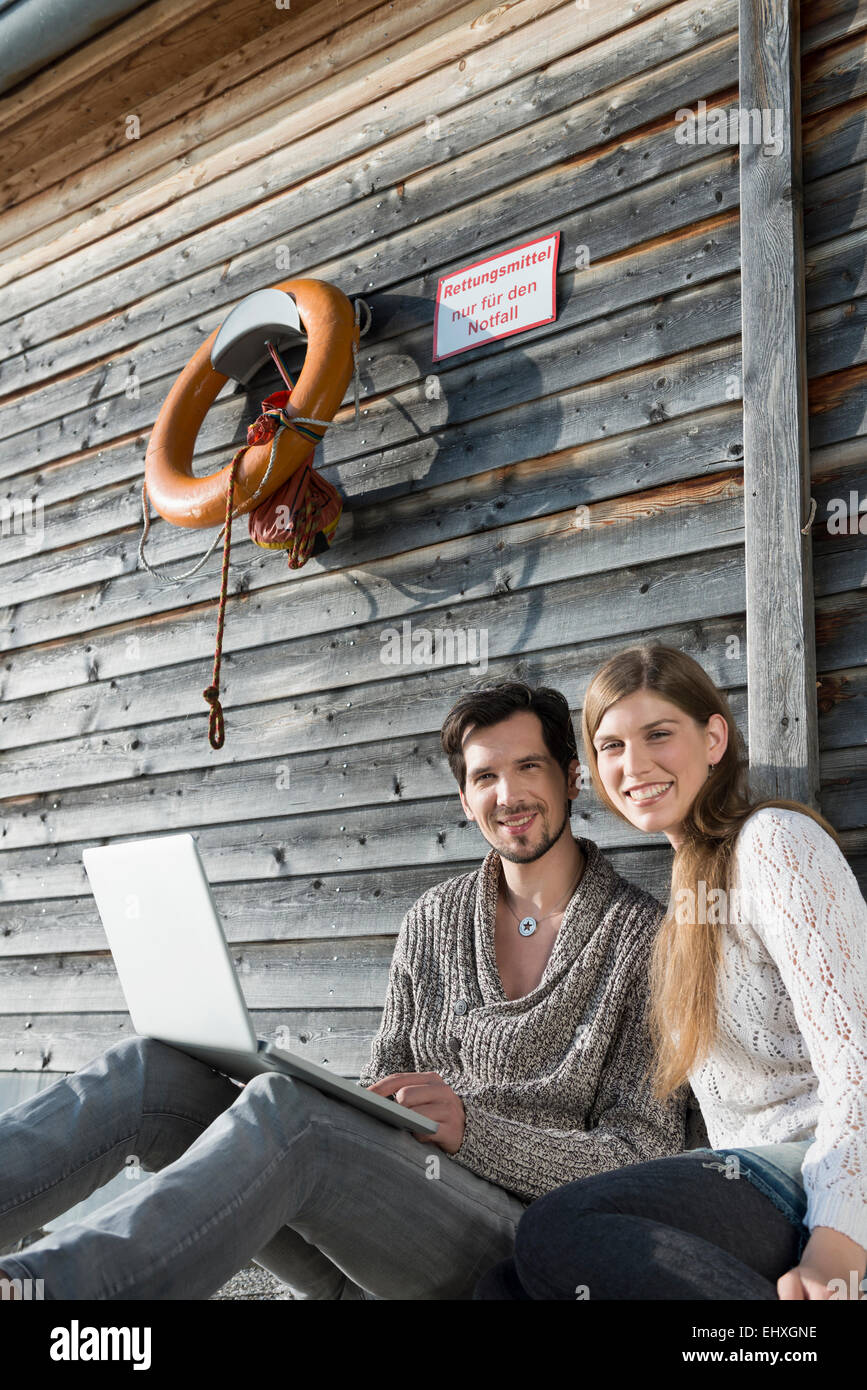 portrait young couple sitting wooden wall laptop Stock Photo - Alamy