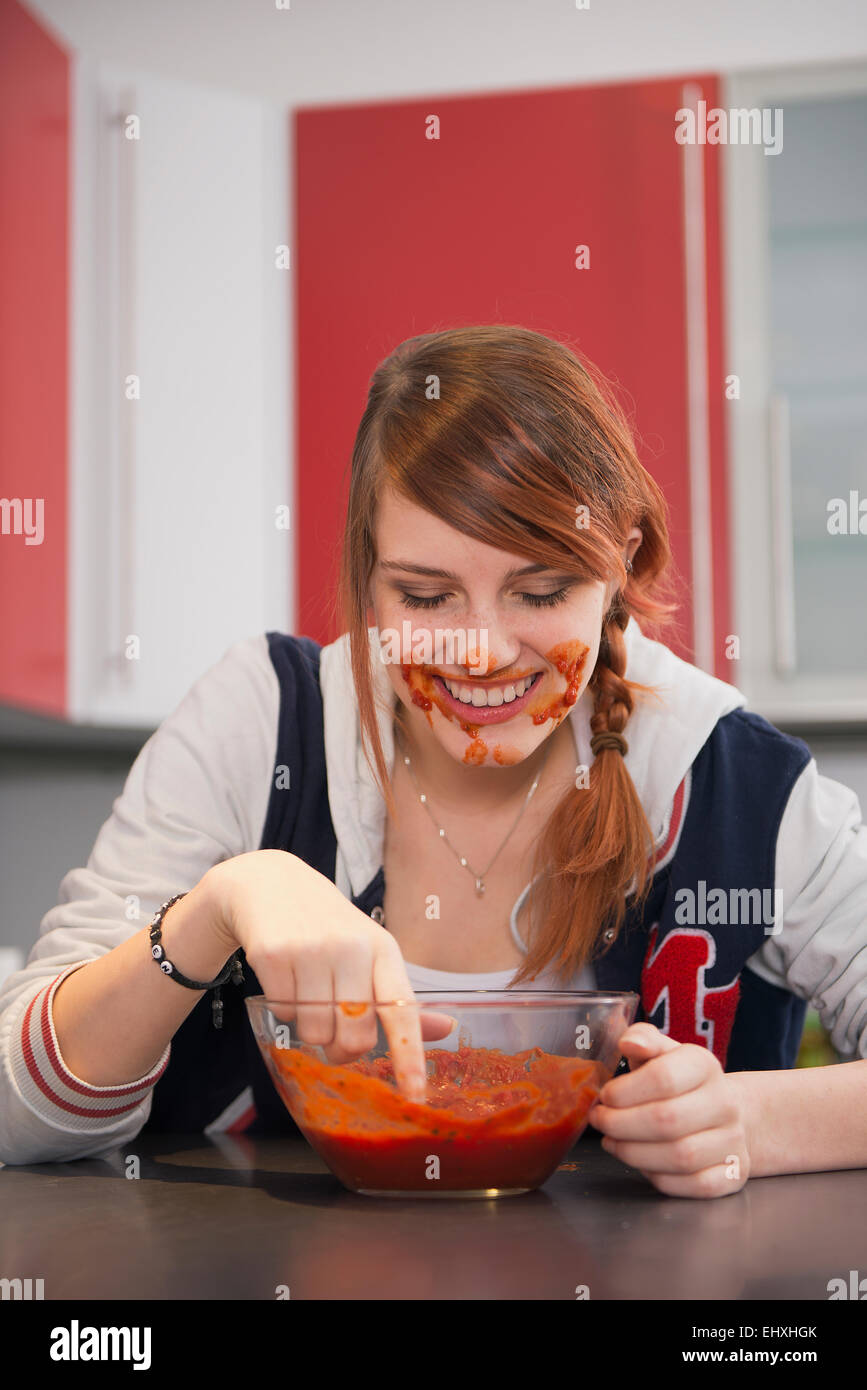 young-woman-eating-tomato-sauce-in-kitchen-munich-bavaria-germany-EHXHGK.jpg