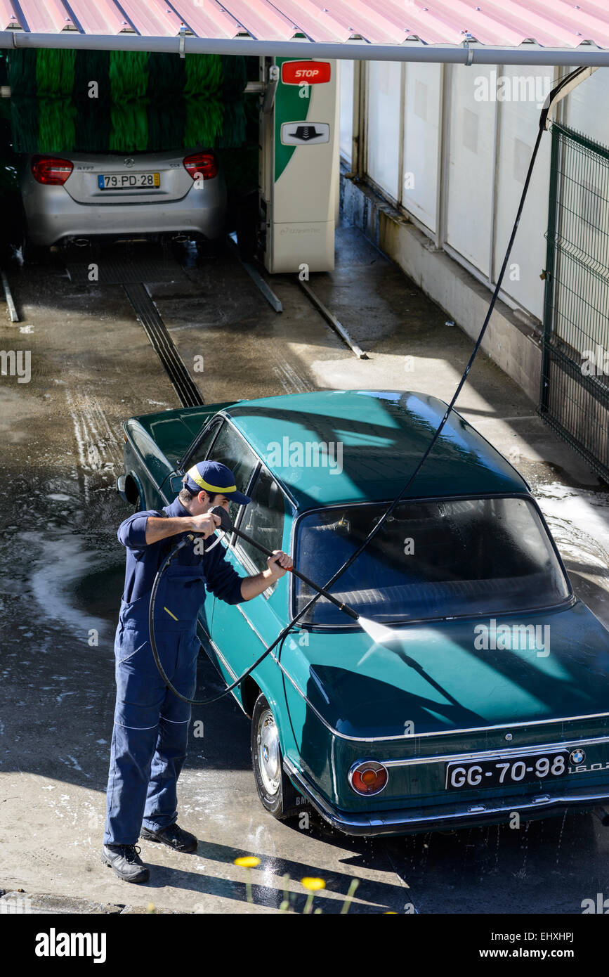 Young man washing car with high pressure water hose at a professional car wash Stock Photo