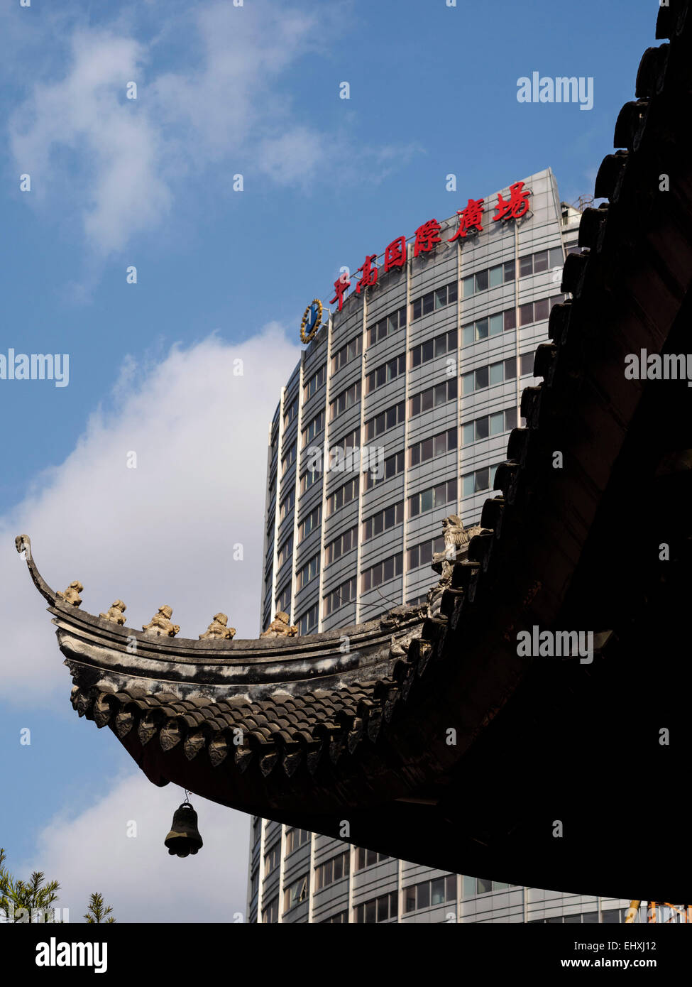 Detail of the ornate rooftop of the Jade Buddha temple next to a modern building in Shanghai, China Stock Photo