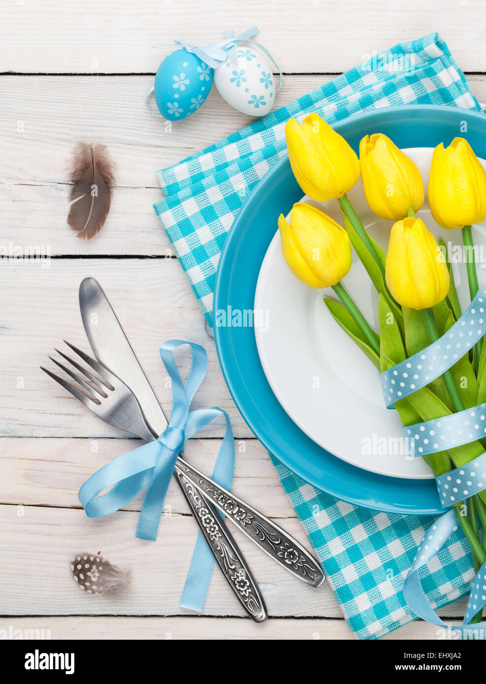 Easter with yellow tulips and colorful eggs over white wooden table ...