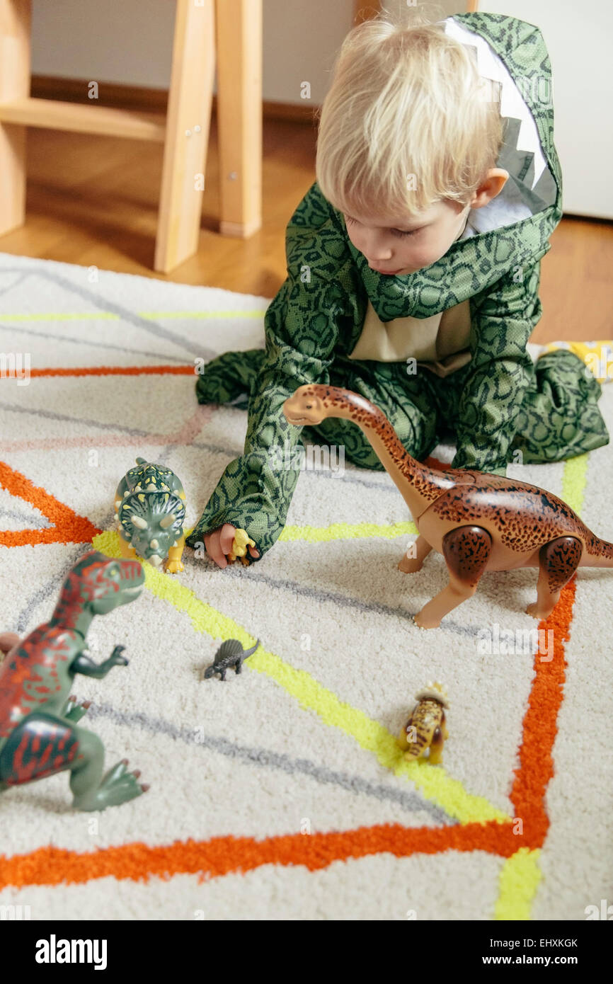 Little boy wearing dinosaur costume playing with toy dinosaurs Stock Photo Alamy