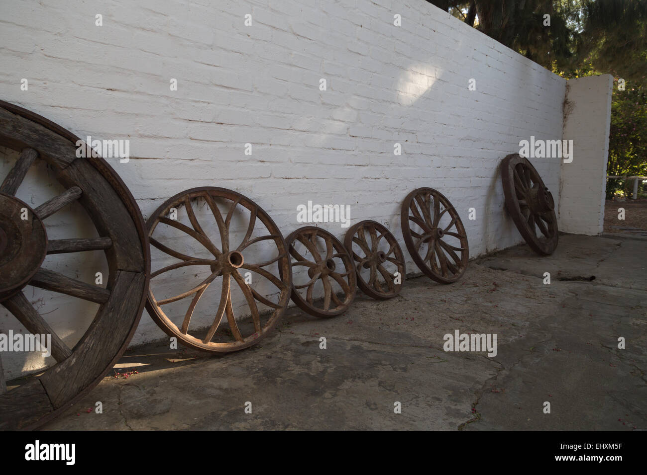 Old wooden wagon wheels propped up against a whitewashed wall in a quaint South African farmhouse in Montagu, Western Cape. Stock Photo