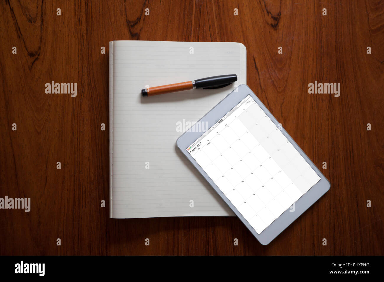 Digital tablet and ballpen lying on opened notebook Stock Photo
