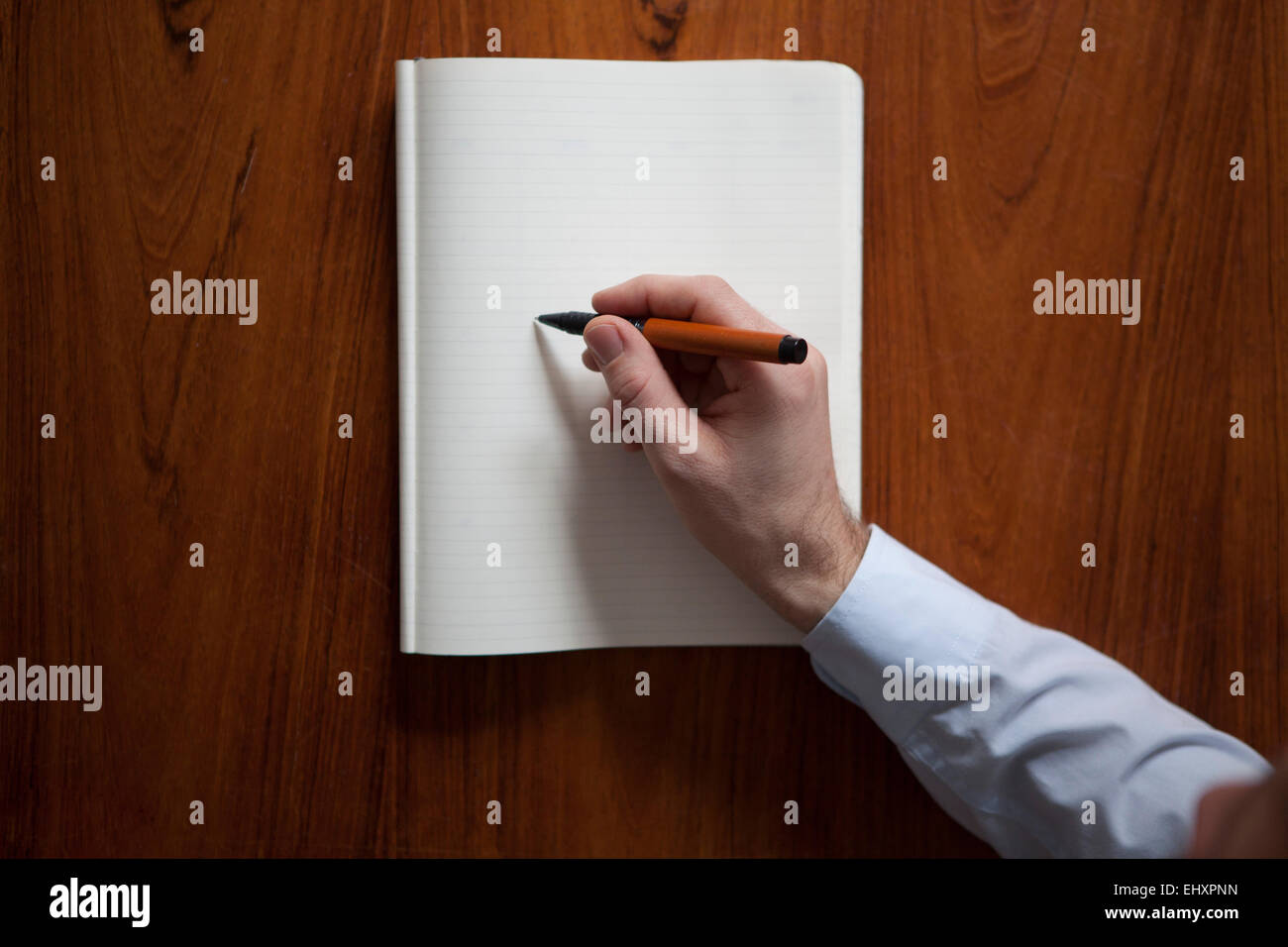 Man's hand writing with ballpen in notebook Stock Photo