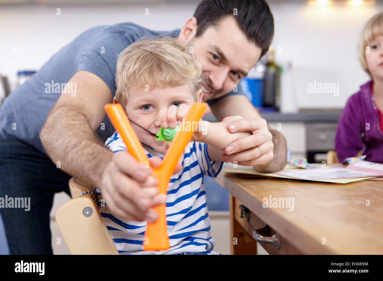 Little boy in kitchen learning to use slingshot Stock Photo