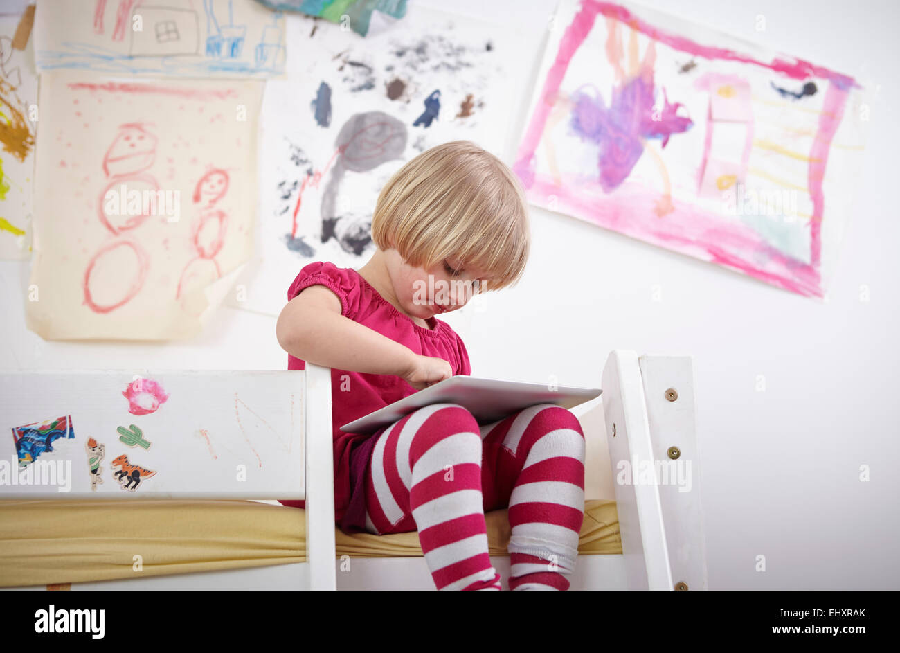 Little girl sitting on bunk bed, drawing on touch pad Stock Photo