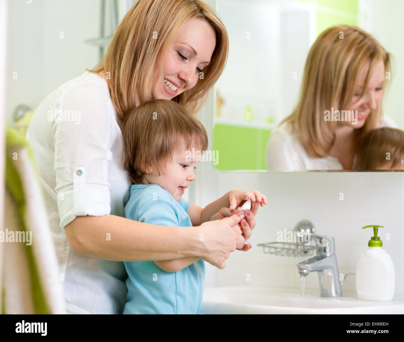 mother teaches kid washing hands in bathroom Stock Photo