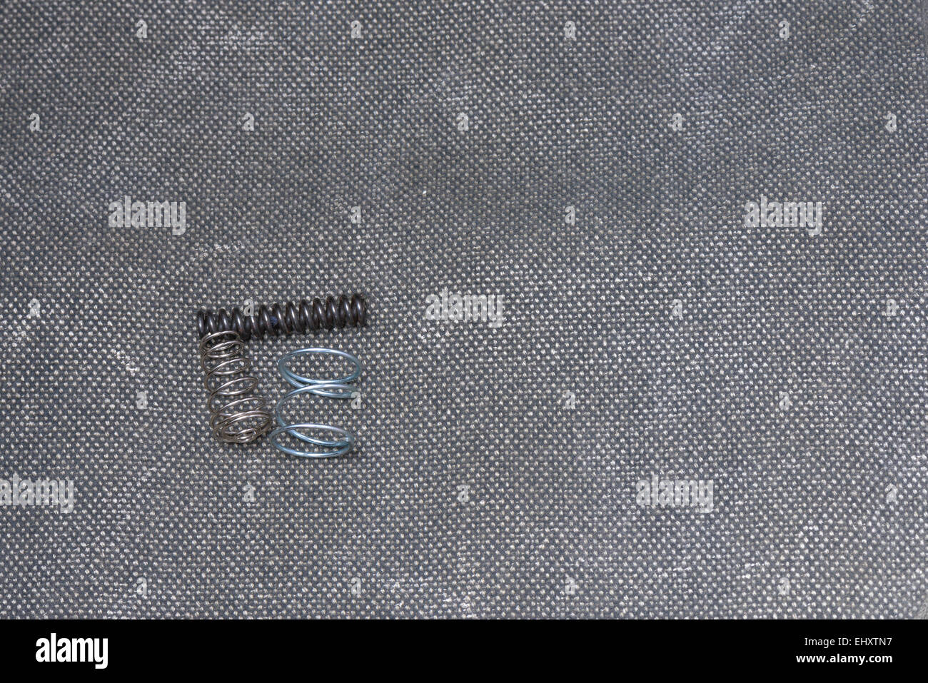 Three Steel springs on a grey texile background Stock Photo