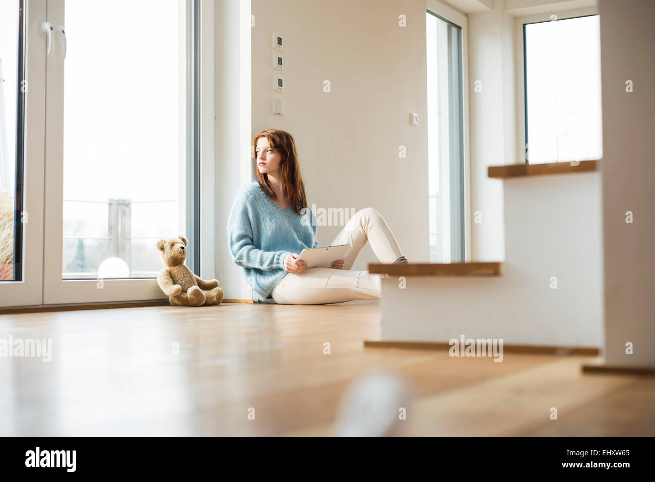 Young woman sitting on floor next to teddy bear Stock Photo - Alamy