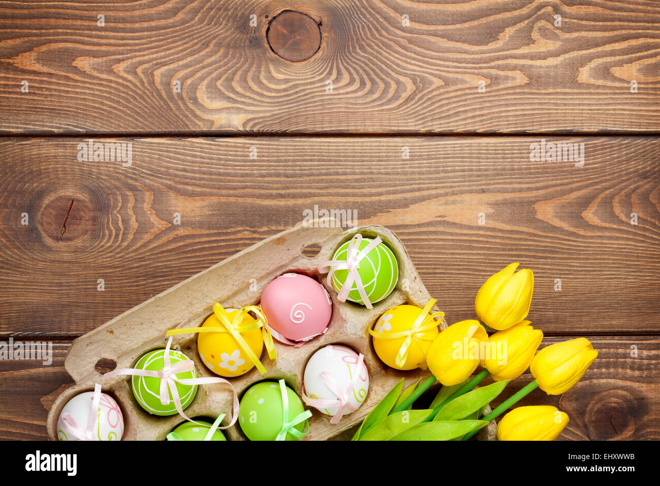 Easter background with colorful eggs and yellow tulips over wood. Top ...