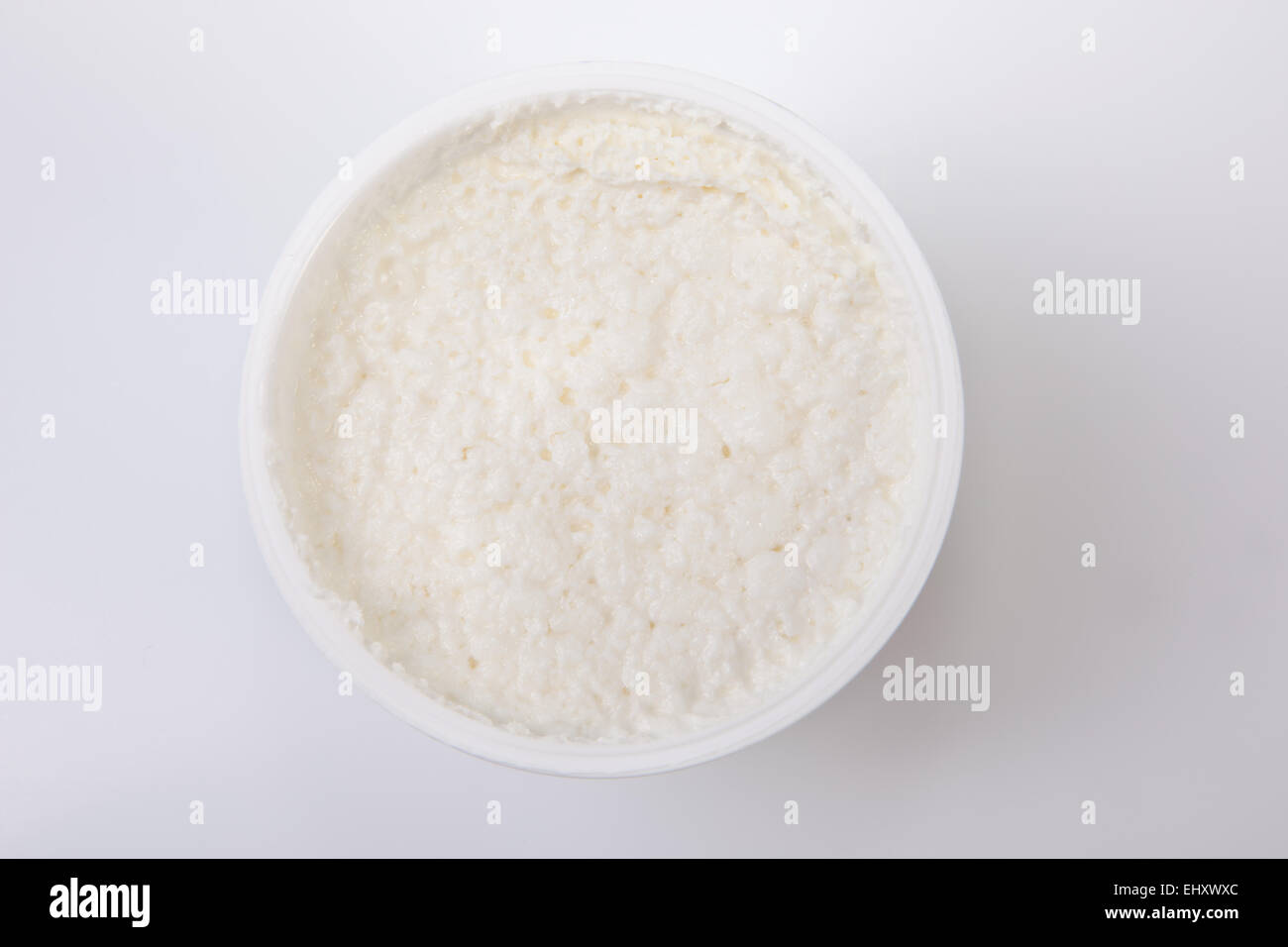 Granulated cottage cheese its plastic bowl. Isolated over white background Stock Photo