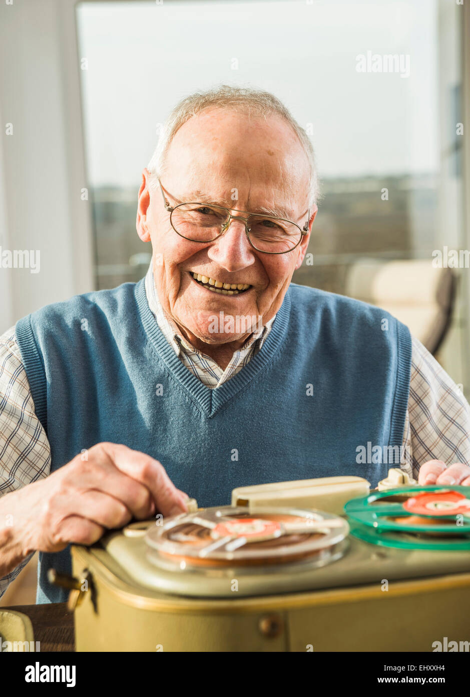 Smiling senior man operating old-fashioned recorder Stock Photo