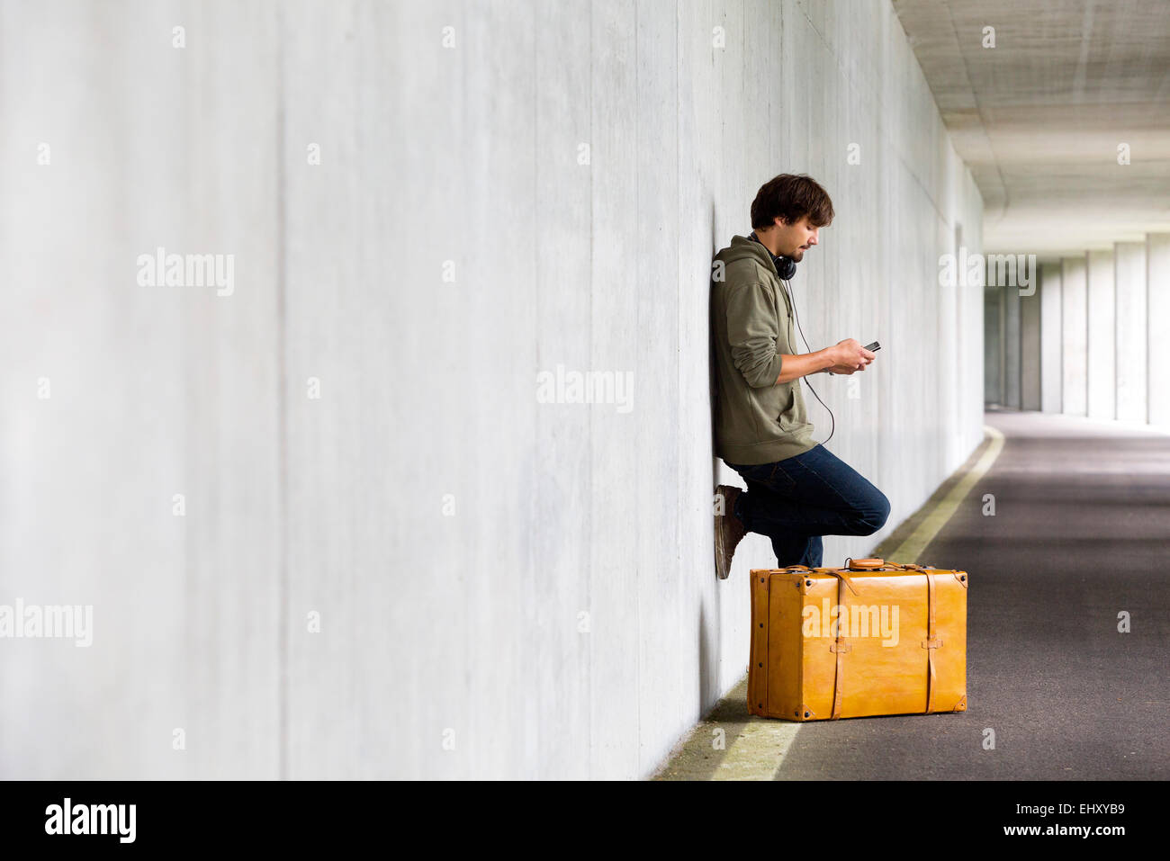 Man with leather suitcase and smartphone waiting in a car park Stock Photo