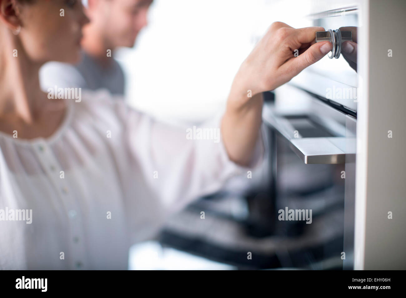 Woman adjusting temperature of oven Stock Photo Alamy