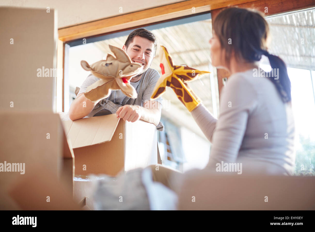 Couple moving house playing with animal hand puppets Stock Photo