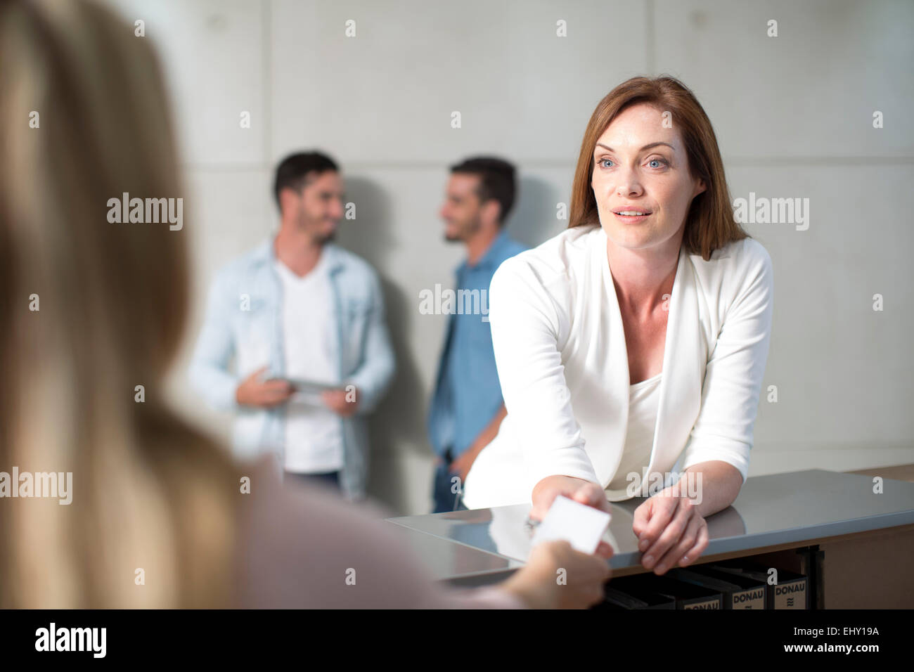 Businesswoman speaking to receptionist over counter Stock Photo