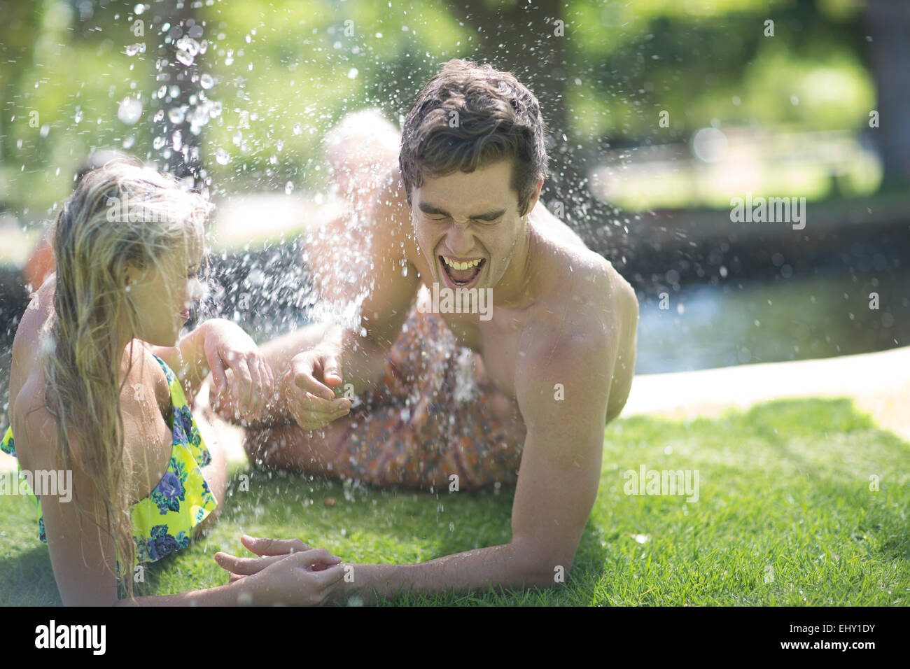 Young couple on holiday getting splashed near a swimming pool Stock Photo