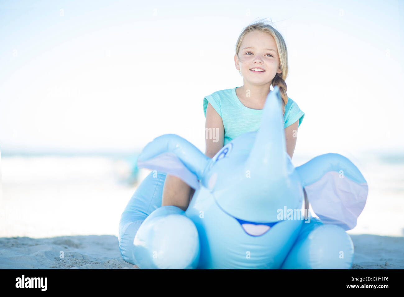 Smiling girl on beach sitting on an inflatable elephant Stock Photo