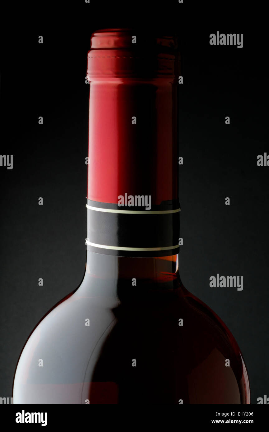 Red wine bottle closeup with red capsule and black background Stock Photo