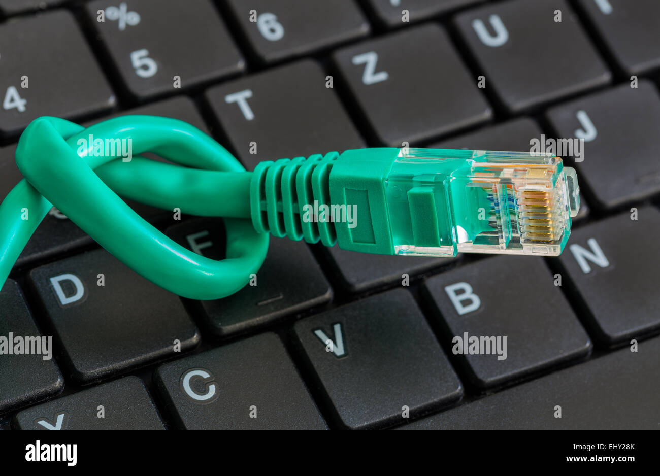Network cable with green knot and keyboard. Stock Photo