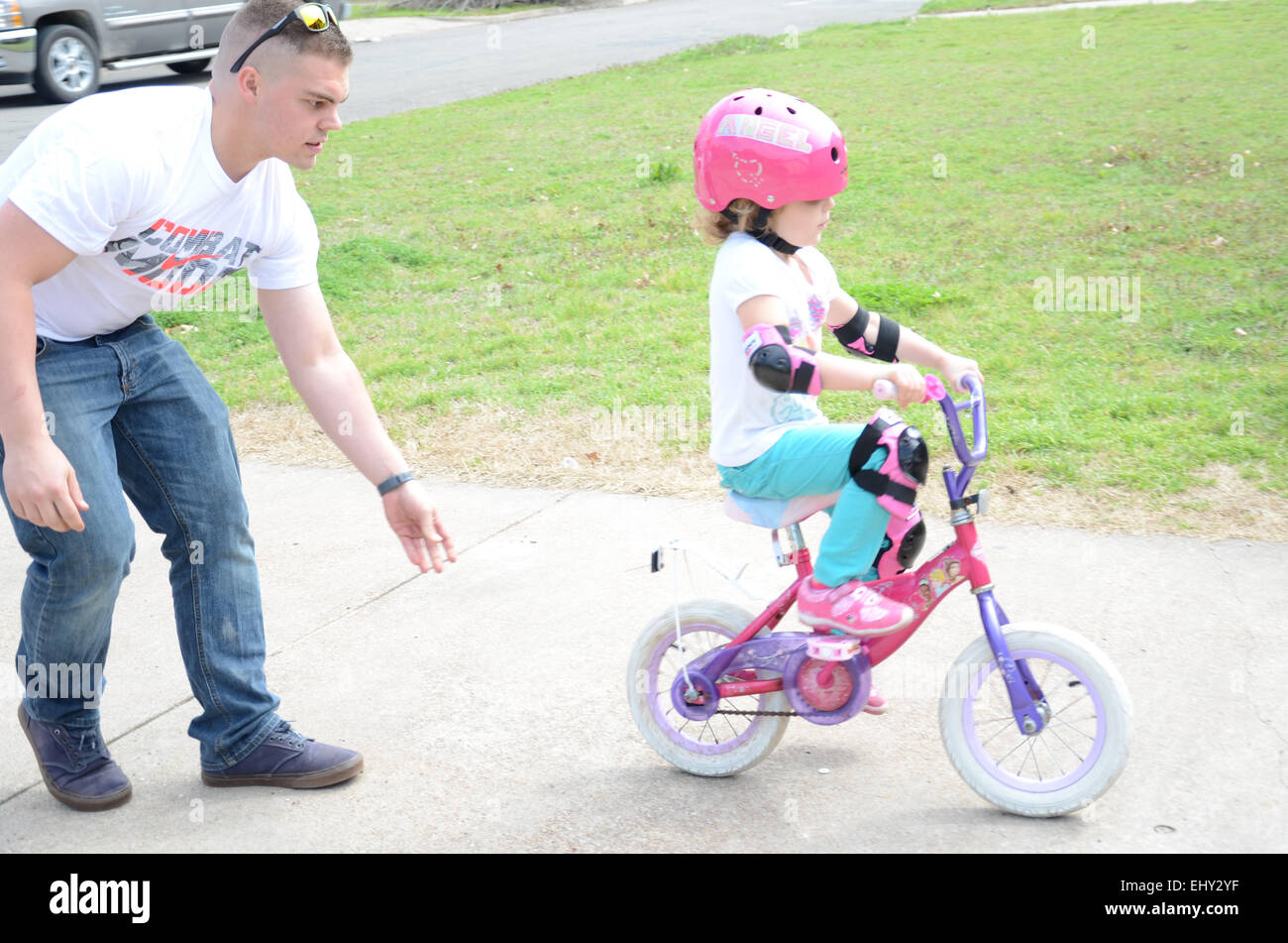 Father teaching daughter to ride a bike. Stock Photo