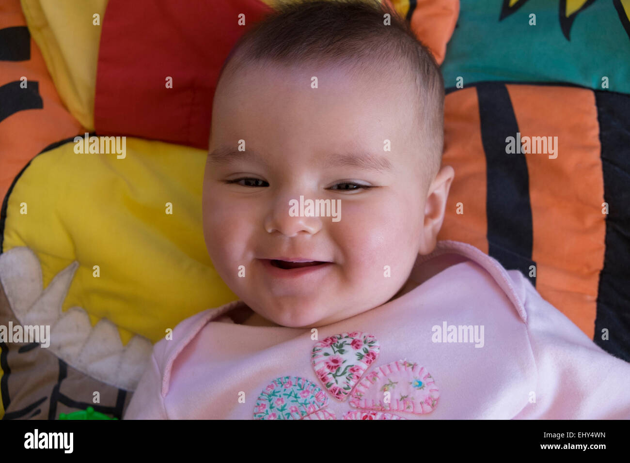 8 month old baby girl, lying on floor, smiling Stock Photo