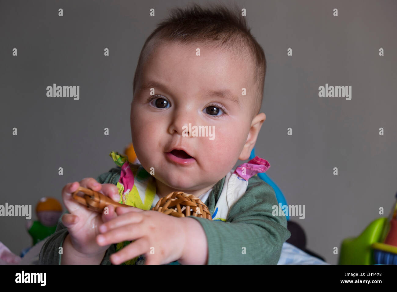 8 month old baby girl, surrounded by toys in baby bouncer, playing Stock Photo