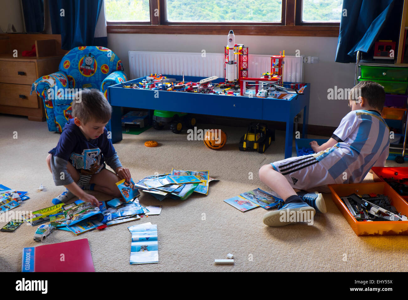 Brothers aged  aged four and six years playing with Lego building blocks in bedroom Stock Photo