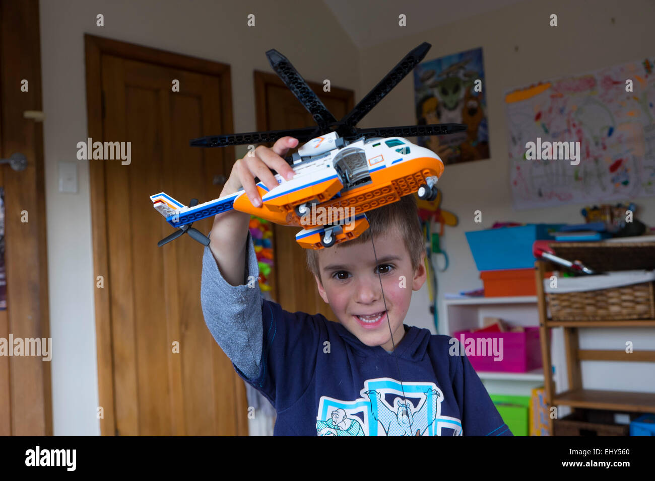 Boy aged four years playing with Lego building blocks helicopter, in bedroom Stock Photo