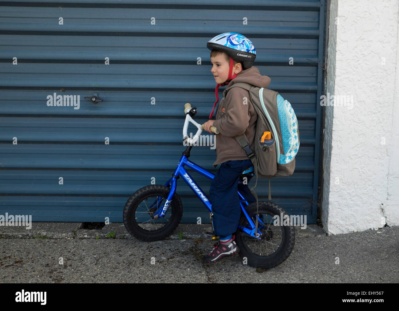 Four year old boy with backpack on bike with helmet Stock Photo