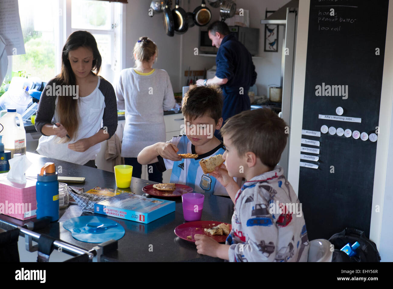 Family in kitchen preparing and eating food Stock Photo