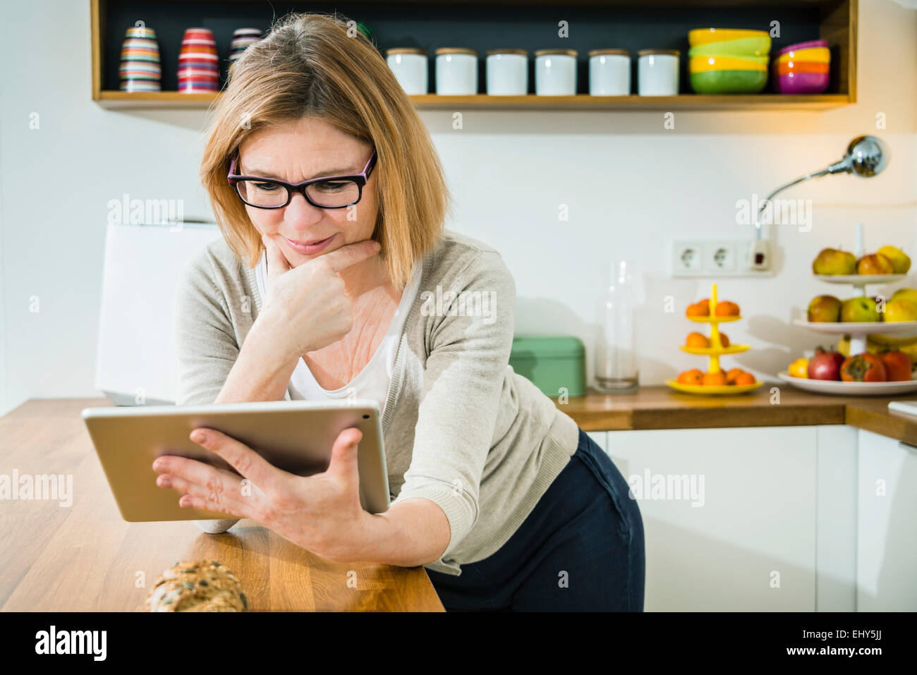 Senior woman in kitchen using tablet pc Stock Photo