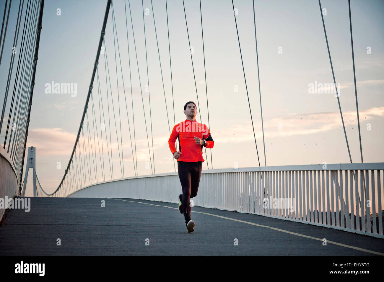 Man with headphones jogging on bridge Stock Photo