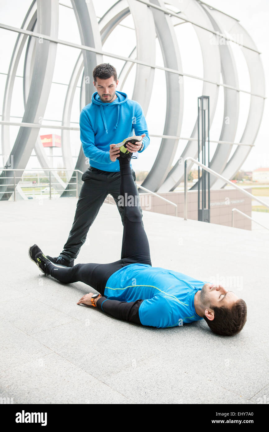 Male runners stretching and warming up in city Stock Photo