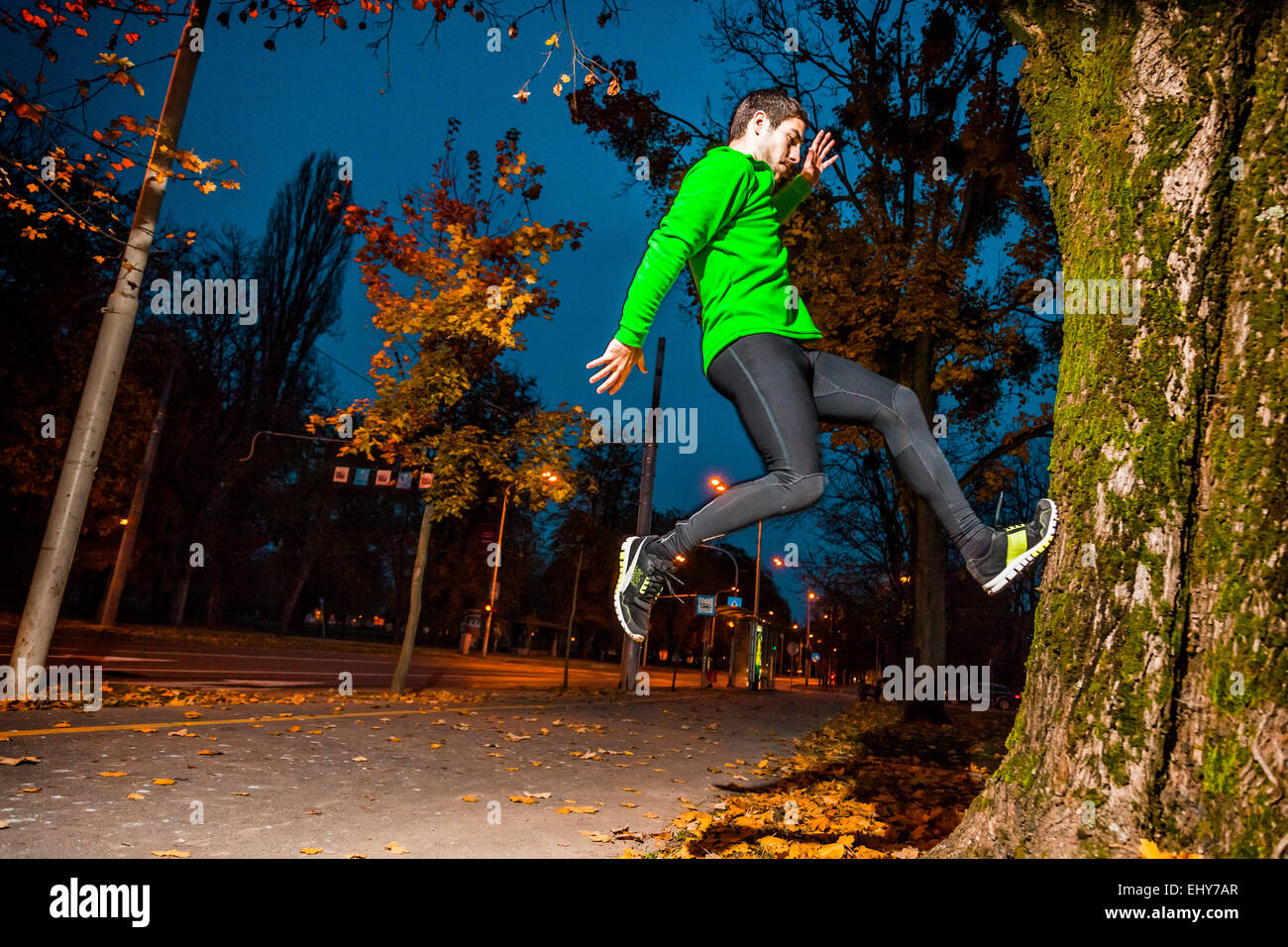 Male runner jumping in park  at twilight Stock Photo