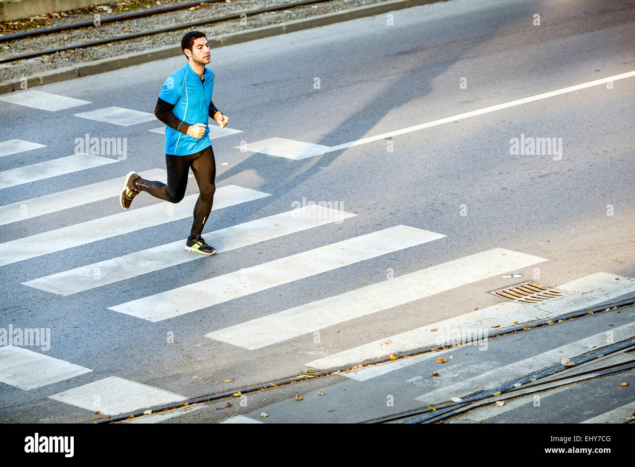 Male runner jogging on crosswalk in city Stock Photo
