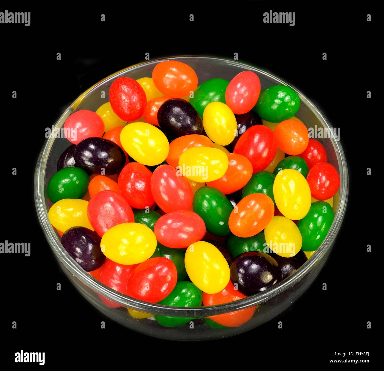 Fruit jelly beans in many colors in a glass bowl on a black background